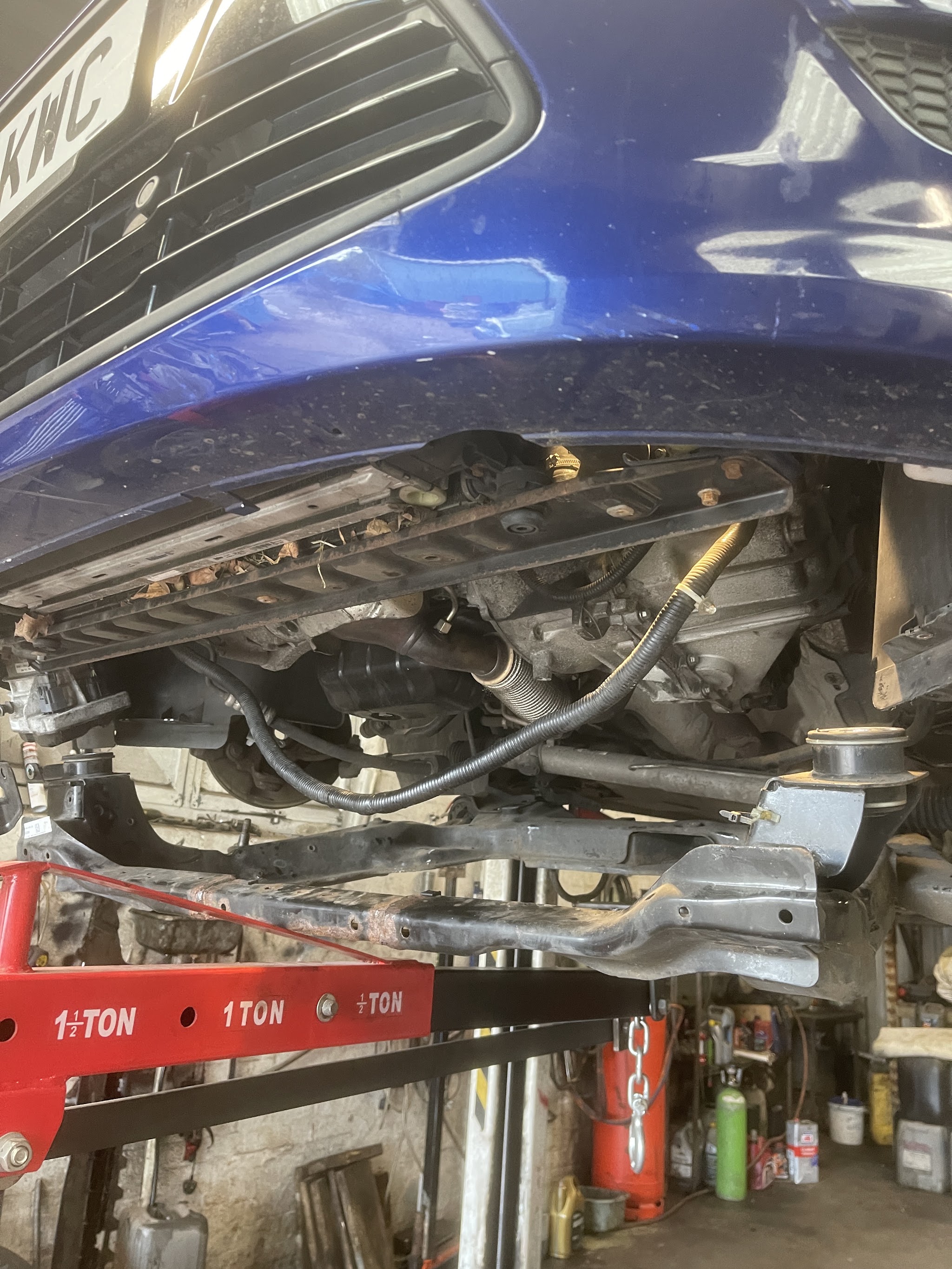 Blue car raised on the lift with the subframe lowered and an engine crane alongside