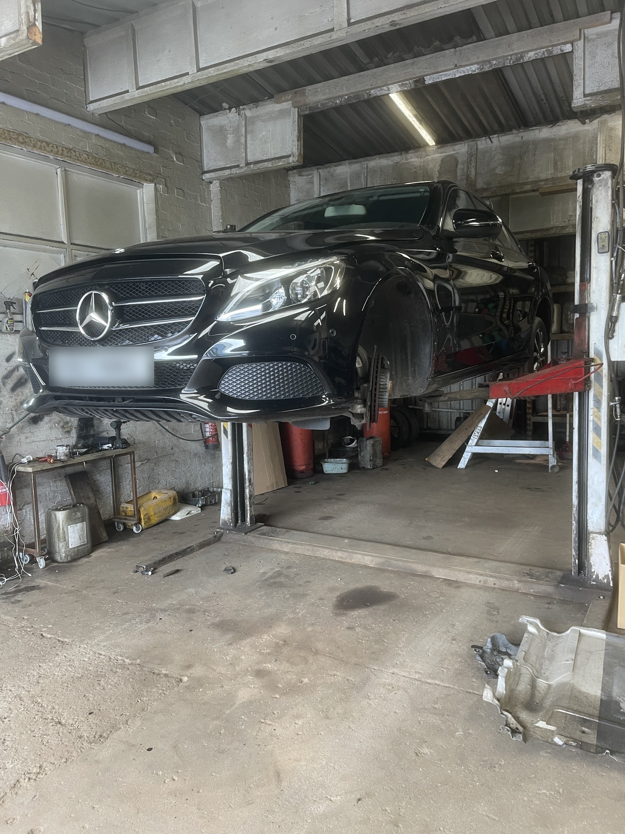 A black Mercedes raised on the two-post lift inside the MCI AuTo&MoTo workshop